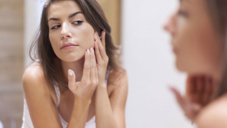 Woman checking her skin in a mirror