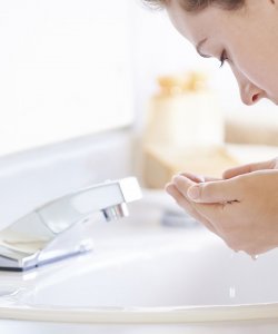 Woman washing her face with water